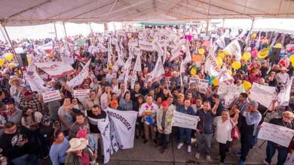 Carlos Torres Piña hablando ante una multitud numerosa en un evento al aire libre en Zacapu o Zitácuaro, Michoacán, con banderas y pancartas visibles