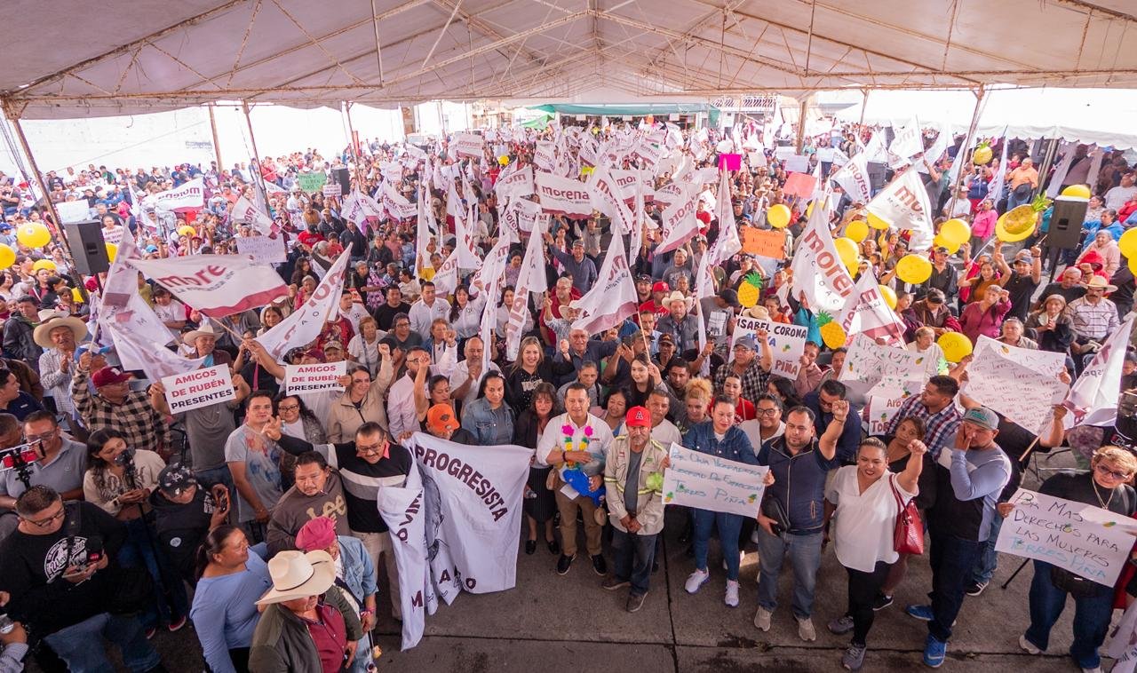 Carlos Torres Piña hablando ante una multitud numerosa en un evento al aire libre en Zacapu o Zitácuaro, Michoacán, con banderas y pancartas visibles