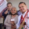 Carlos Torres Piña hablando ante público en Morelia durante evento conmemorativo del Día de las Abuelas y los Abuelos, con bandera de México y logo de programas de bienestar