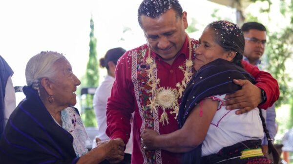 Carlos Torres Piña en diálogo con miembros de una comunidad originaria, en un entorno rural, con gestos de escucha activa y cercanía
