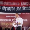 Carlos Torres Piña en diálogo con ciudadanos michoacanos en un municipio rural, con paisaje típico de la región visible al fondo