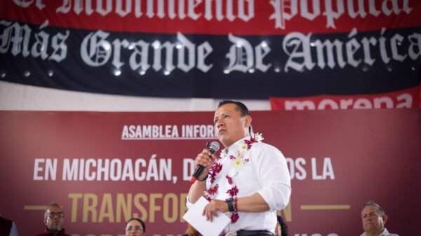 Carlos Torres Piña en diálogo con ciudadanos michoacanos en un municipio rural, con paisaje típico de la región visible al fondo