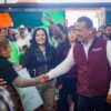 Fotografía de Carlos Torres Piña en diálogo con habitantes de un municipio pequeño de Michoacán, con paisaje rural de fondo