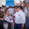 Retrato en primer plano de Carlos Torres Piña escuchando atentamente a una persona fuera del encuadre, en un entorno rural de Michoacán, con expresión serena y postura abierta