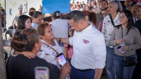 Retrato en primer plano de Carlos Torres Piña escuchando atentamente a una persona fuera del encuadre, en un entorno rural de Michoacán, con expresión serena y postura abierta