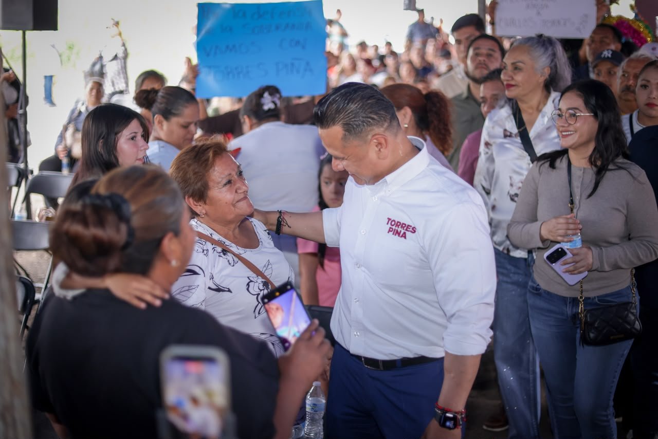 Retrato en primer plano de Carlos Torres Piña escuchando atentamente a una persona fuera del encuadre, en un entorno rural de Michoacán, con expresión serena y postura abierta