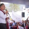 Carlos Torres Piña hablando ante micrófonos y bandera mexicana en un evento público en Morelia, Michoacán