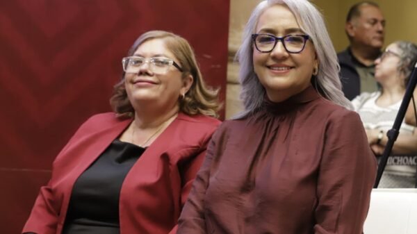Fotografía de la diputada Emma Rivera Camacho hablando ante el pleno del Congreso del Estado de Michoacán, con bandera de Morena visible al fondo.