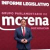 Fotografía de Iván Arévalo Vera hablando ante micrófono en evento del Segundo Informe Legislativo en el Congreso de Michoacán, con bandera estatal visible