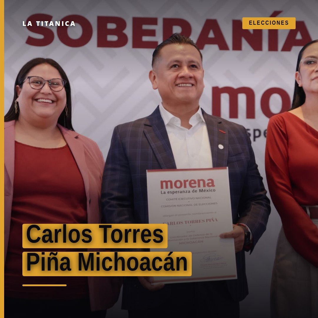 Carlos Torres Piña michoacán hablando frente a una bandera de Morena y símbolos de la transformación, en un acto público en