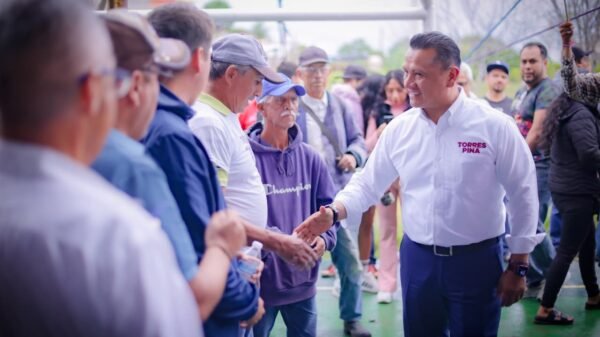 Carlos Torres Piña caminando por una comunidad rural de Michoacán, conversando con habitantes locales, como parte de su