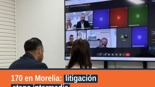 Grupo de personas servidoras públicas en salón de capacitación en Morelia, con material sobre litigación etapa intermedia